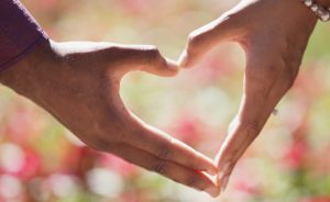 woman holding hands in a heart shape to promote health