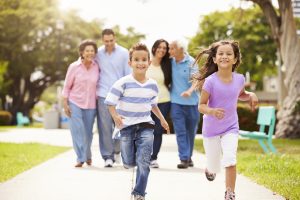 Multi Generation Family Walking In Park Together Children Running Ahead